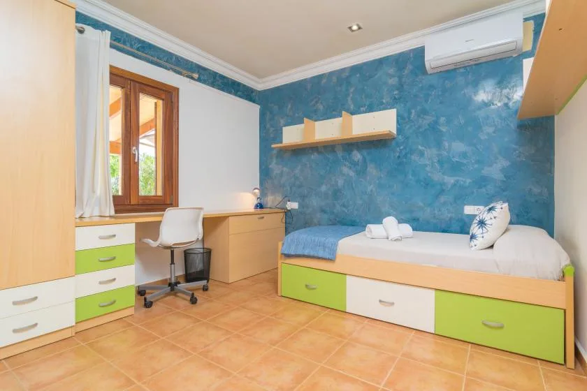 Un dormitorio con una cama individual, un escritorio y paredes azules texturizadas.