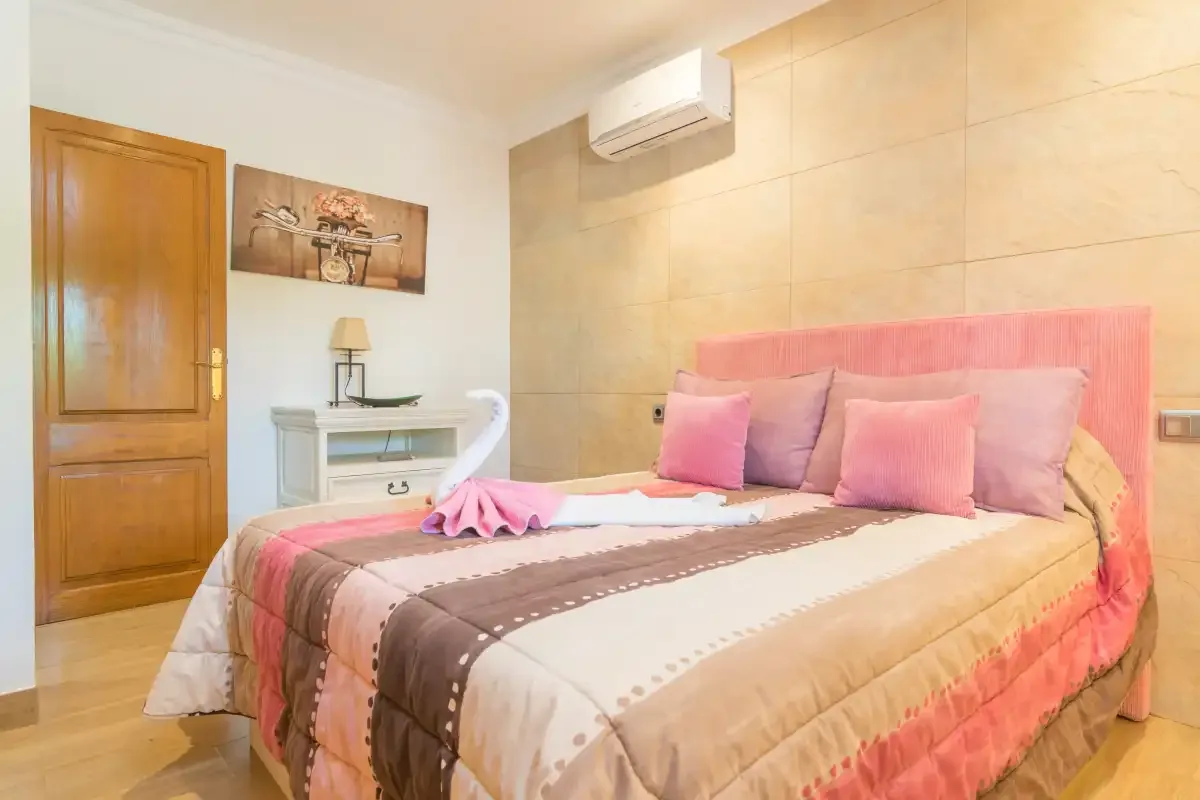 Un dormitorio con una cama vestida con ropa de cama rosa y marrón.