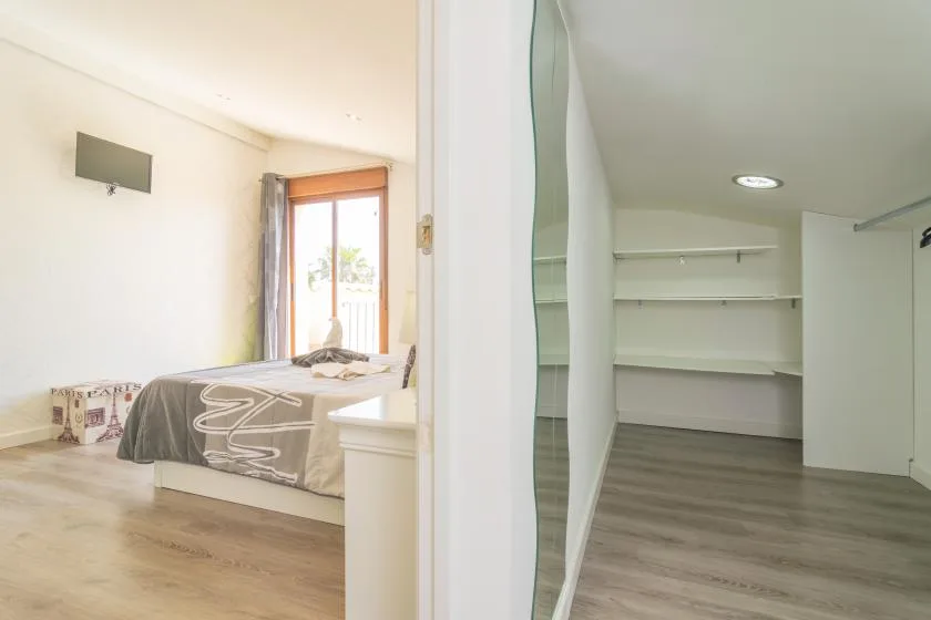 Un dormitorio con una cama junto a un armario abierto.