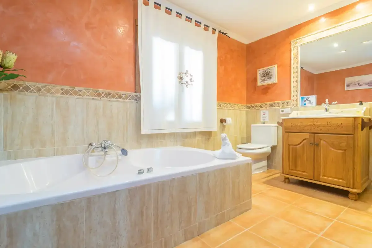 Un baño con bañera, inodoro y lavabo con mueble de madera.