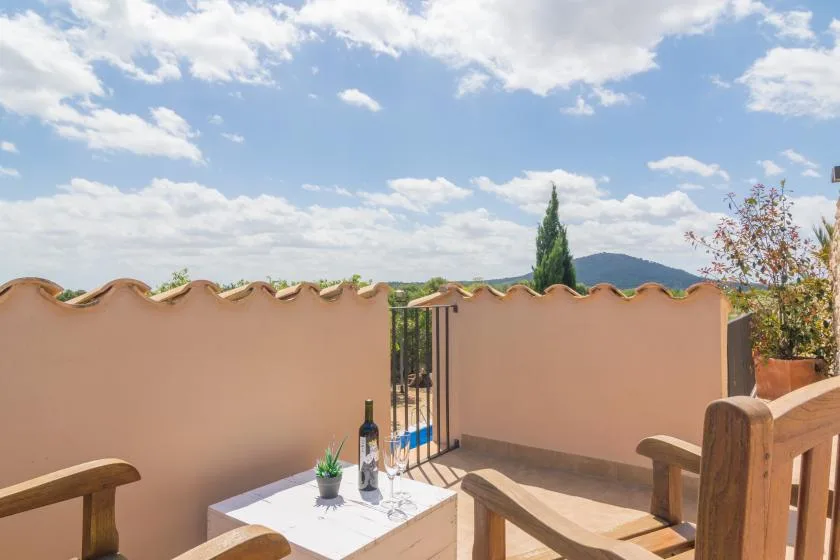 Una terraza al aire libre con asientos, una mesa pequeña y vistas a las colinas cercanas.