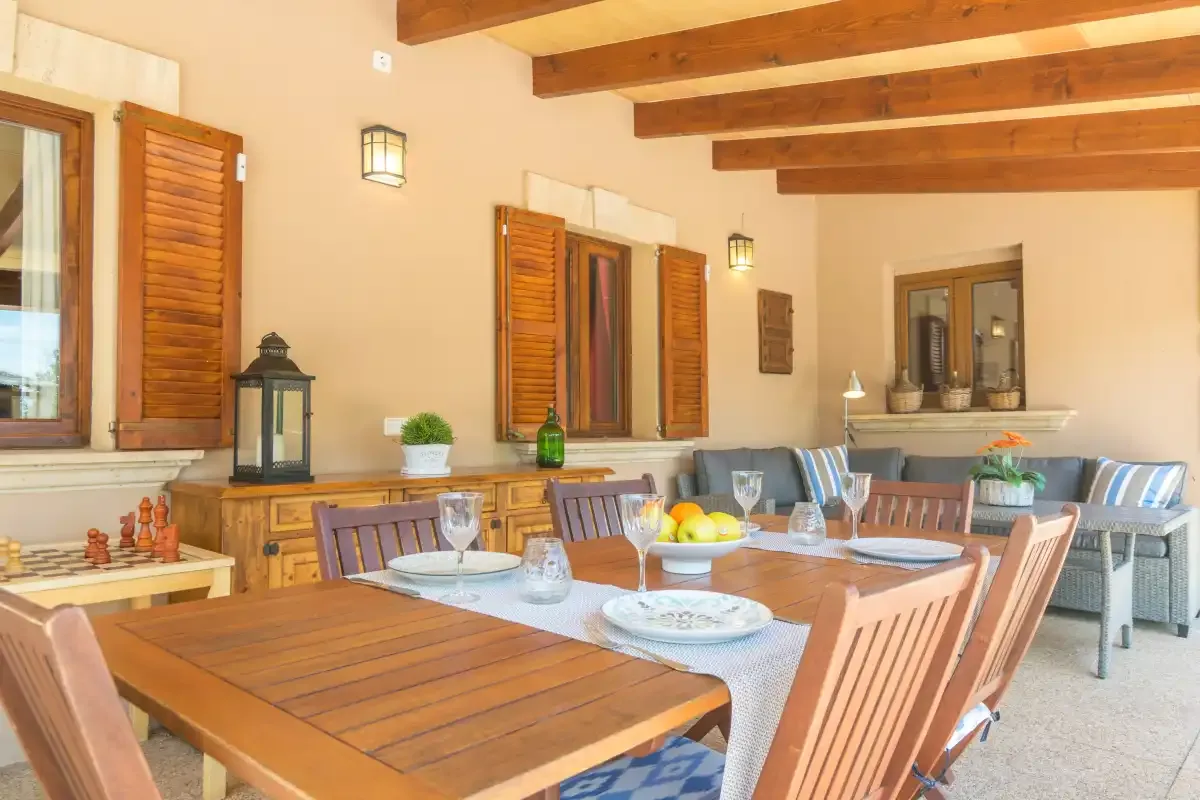 Comedor con una mesa larga de madera bajo vigas de techo a la vista.