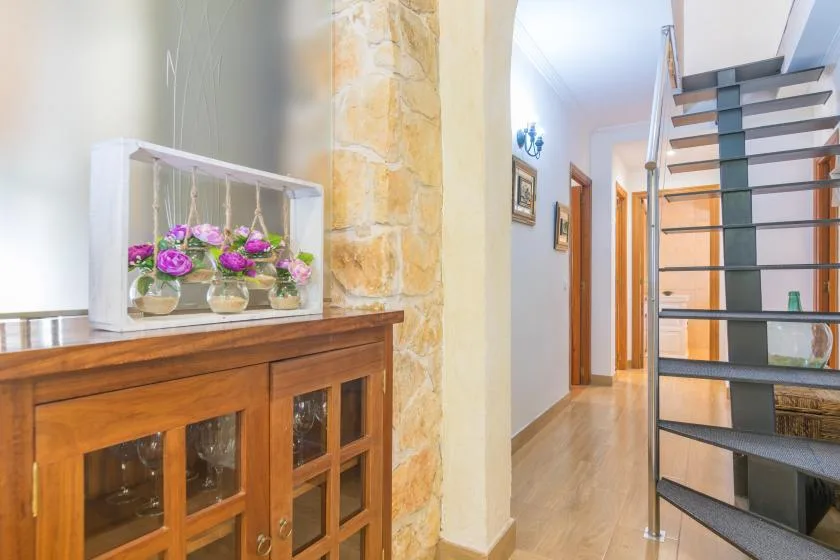 Un pasillo interior con un mueble de madera y una escalera.