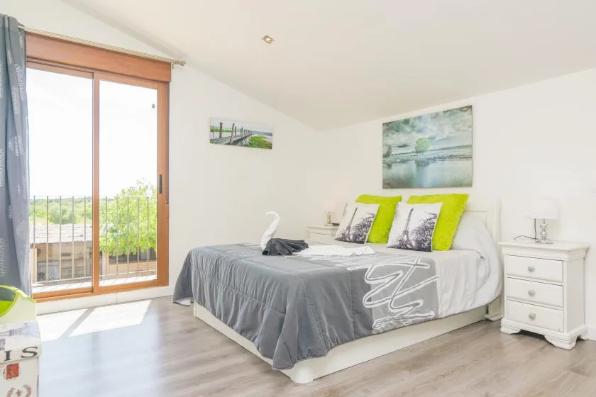 Un dormitorio luminoso con una cama vestida con ropa de cama gris y verde lima.