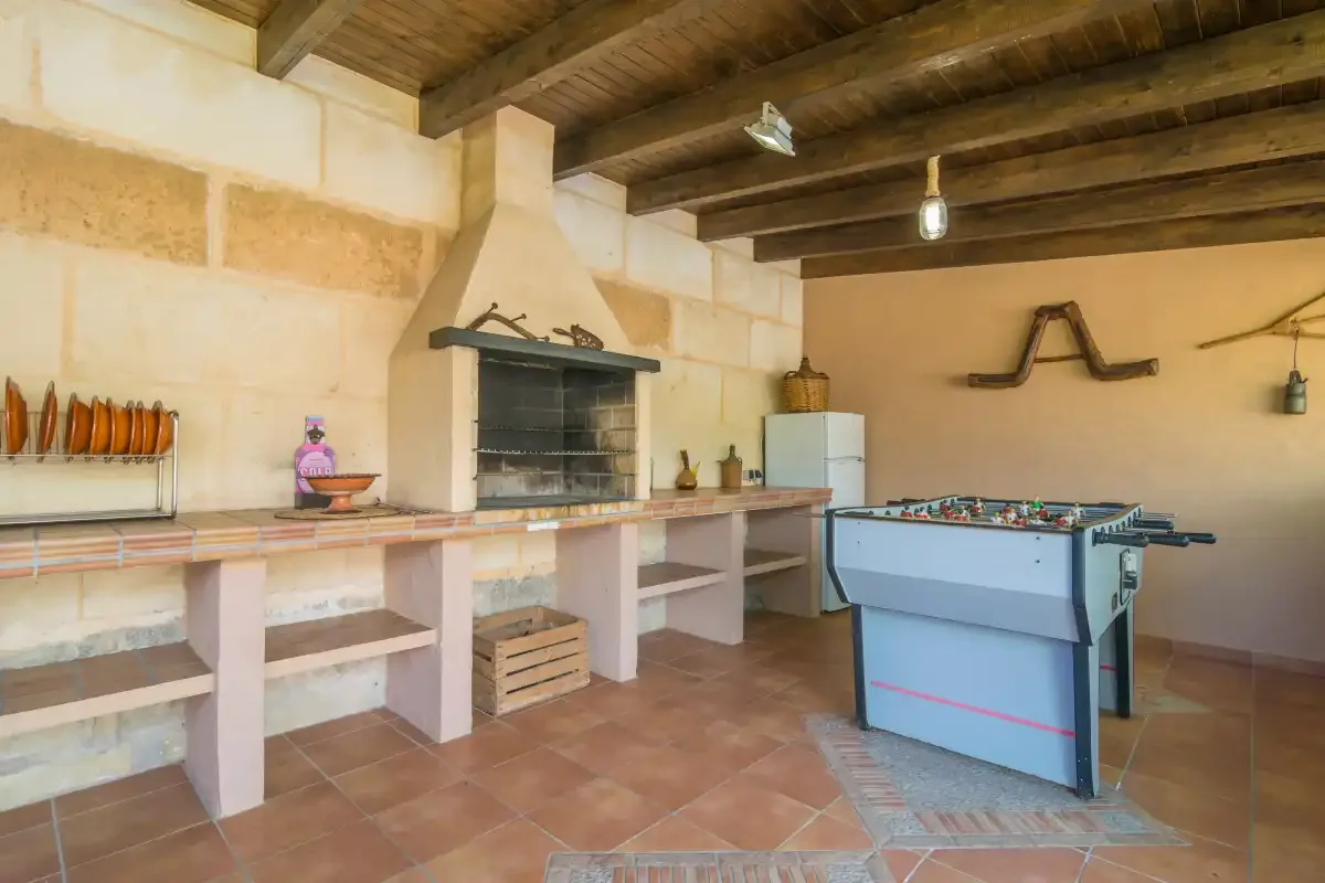 Una sala de recreación rústica tiene una mesa de futbolín junto a una parrilla empotrada.