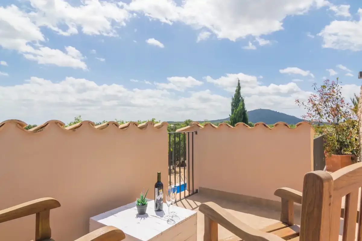 Una terraza soleada con una mesa baja, asientos al aire libre y vistas a las colinas.