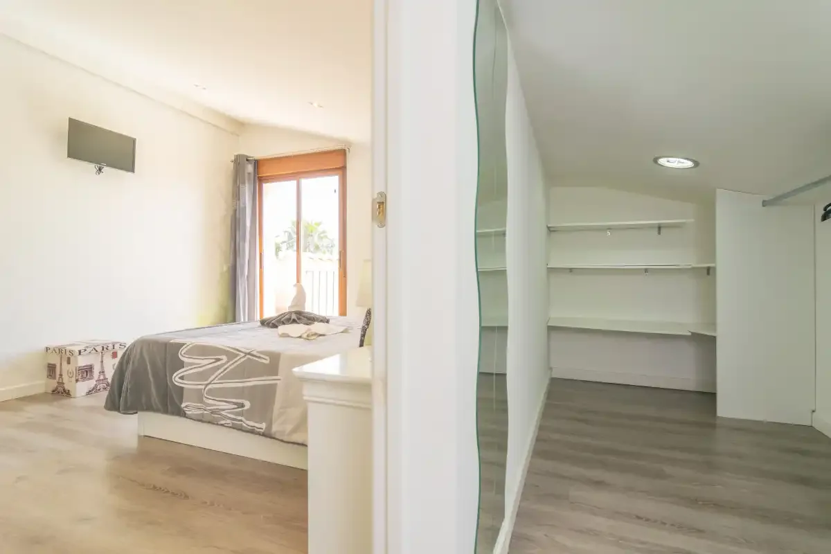 Un dormitorio con una cama junto a un vestidor abierto con estantes.