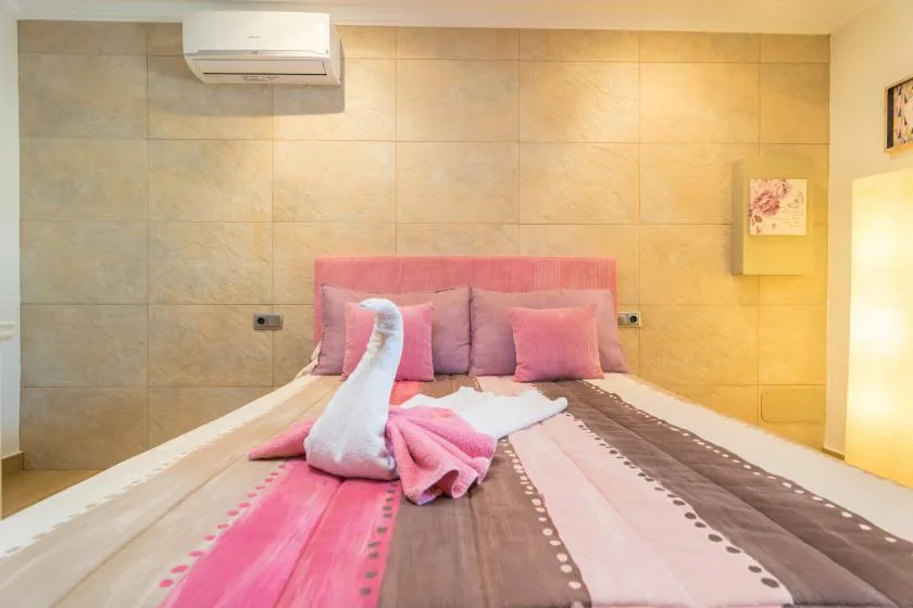 Un dormitorio con una cama vestida con ropa de cama rosa y marrón.