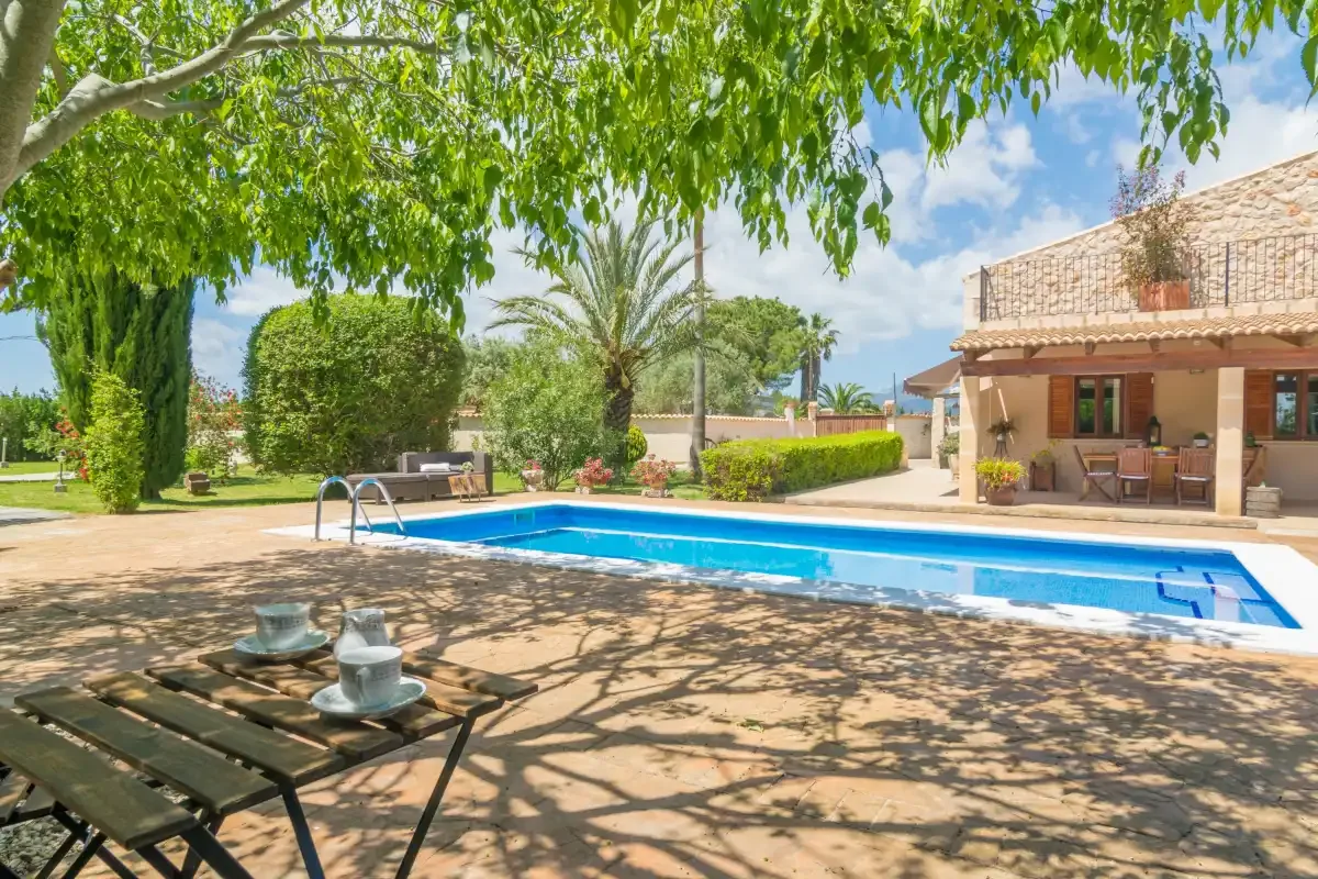 Una piscina al aire libre junto a un patio sombreado y una zona de estar cubierta.
