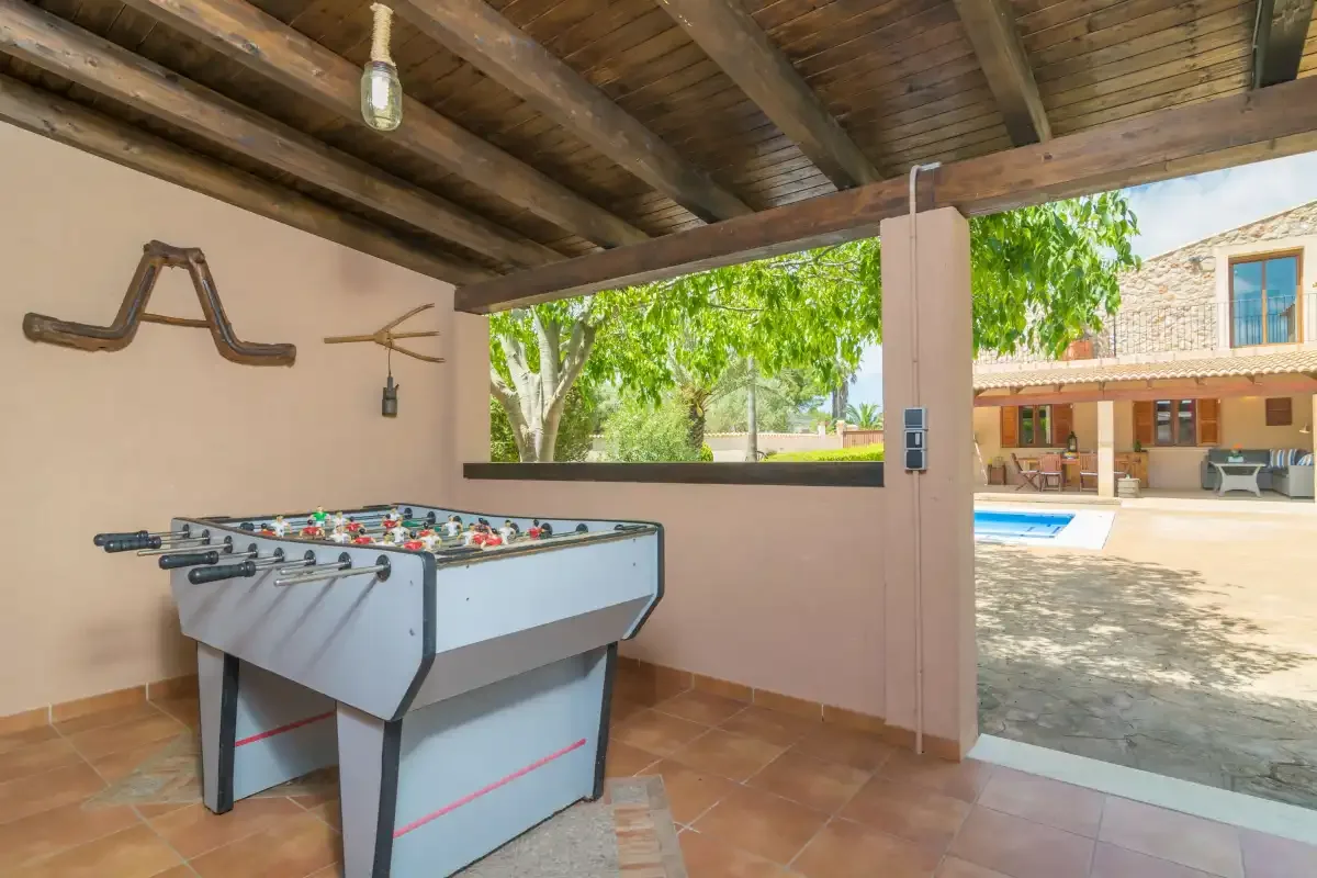 Una zona de juegos cubierta con futbolín, abierta a un patio con piscina.