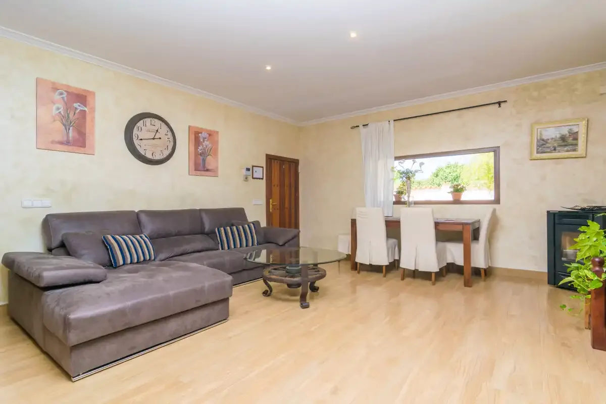 Una sala de estar con asientos seccionales y una mesa de comedor junto a la ventana.