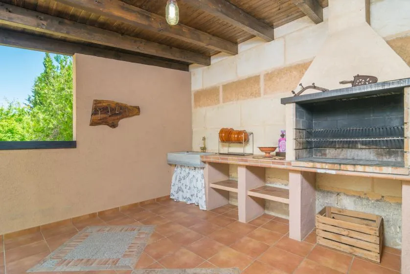 Una zona de cocina cubierta al aire libre con una gran parrilla y una encimera.