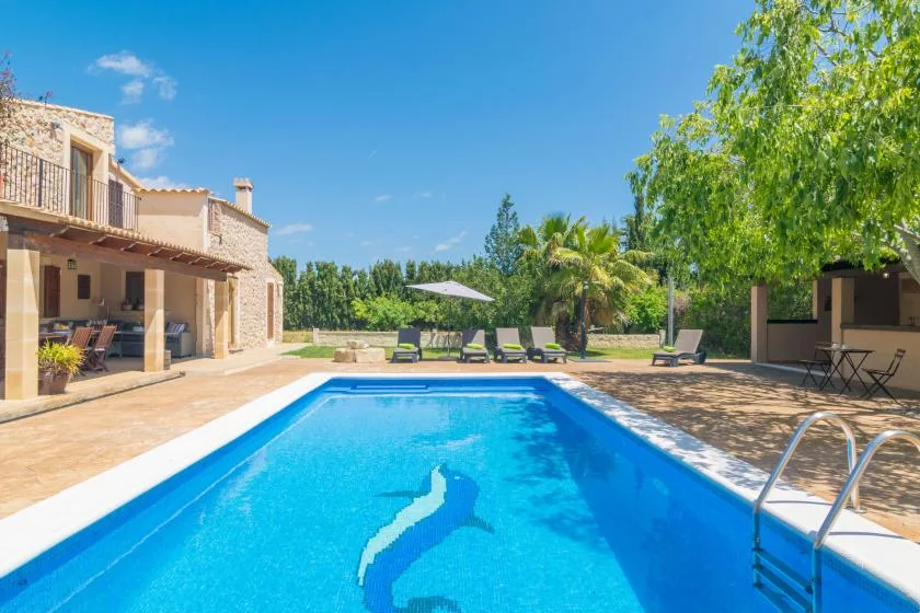 Una piscina al aire libre junto a un patio y una zona de asientos.