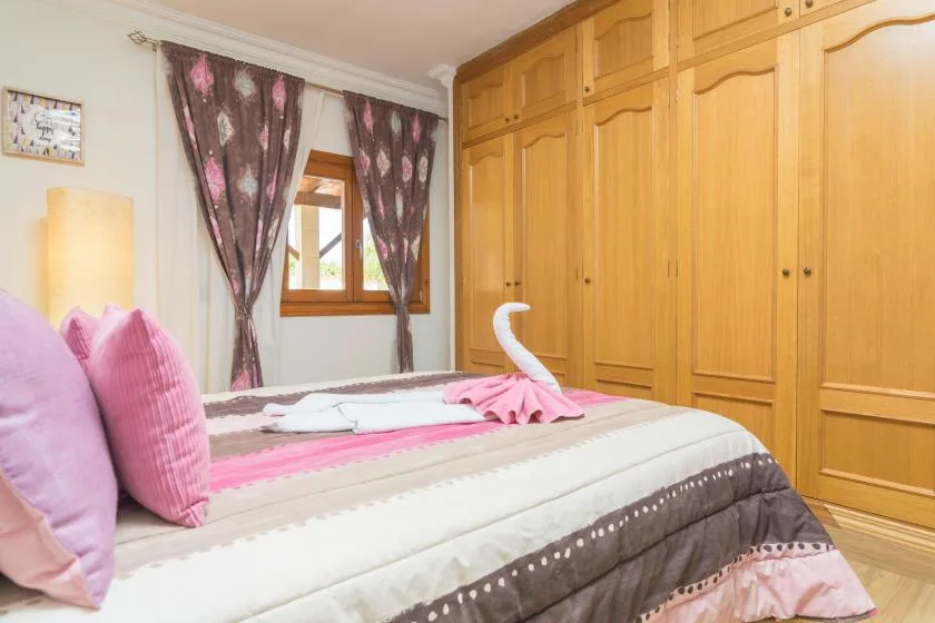 Un dormitorio con una cama, almohadas rosas y armarios empotrados de madera.