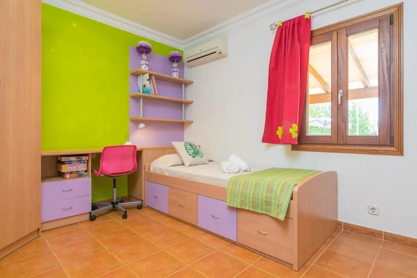 Un dormitorio colorido con cama integrada, escritorio y ventana.