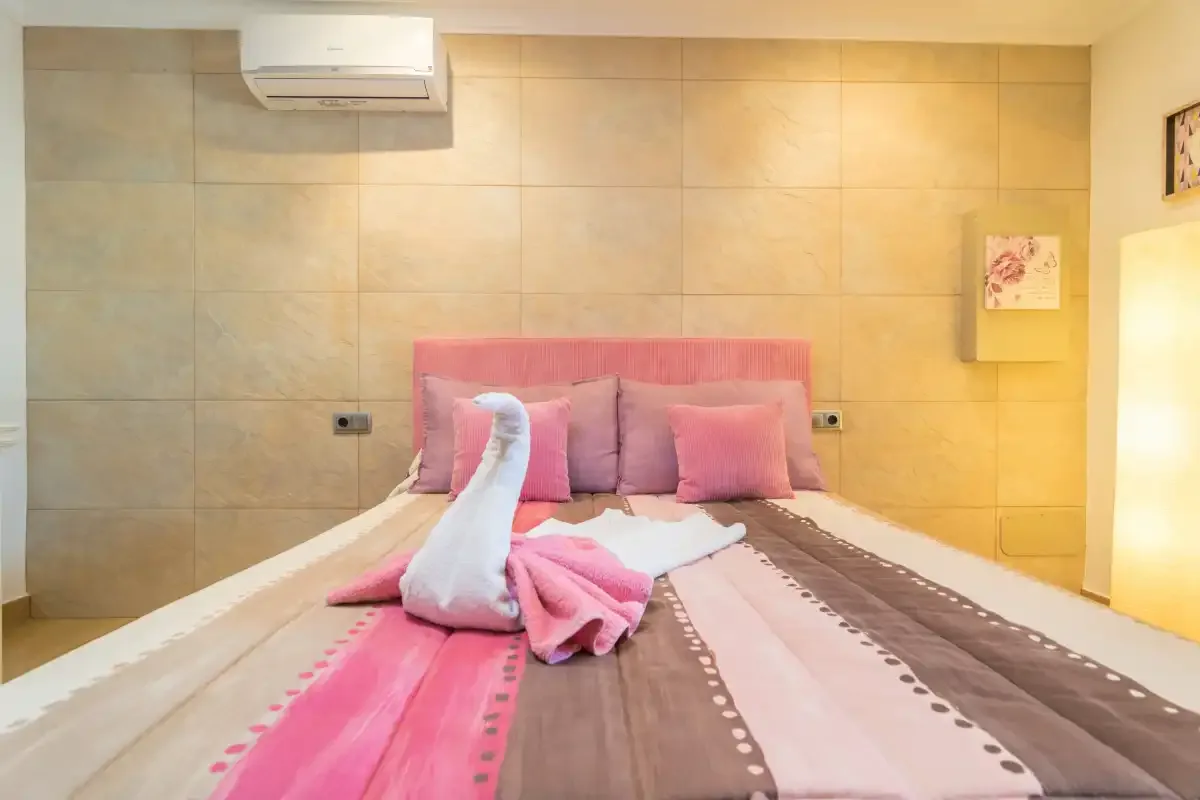 Un dormitorio con una cama vestida con ropa de cama rosa y marrón.