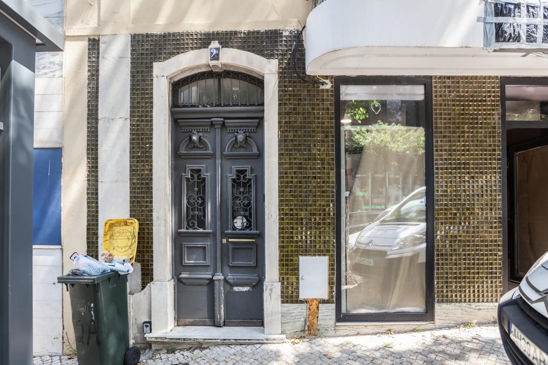Entrada de un edificio a la calle, con una puerta oscura decorativa y fachada de azulejos.