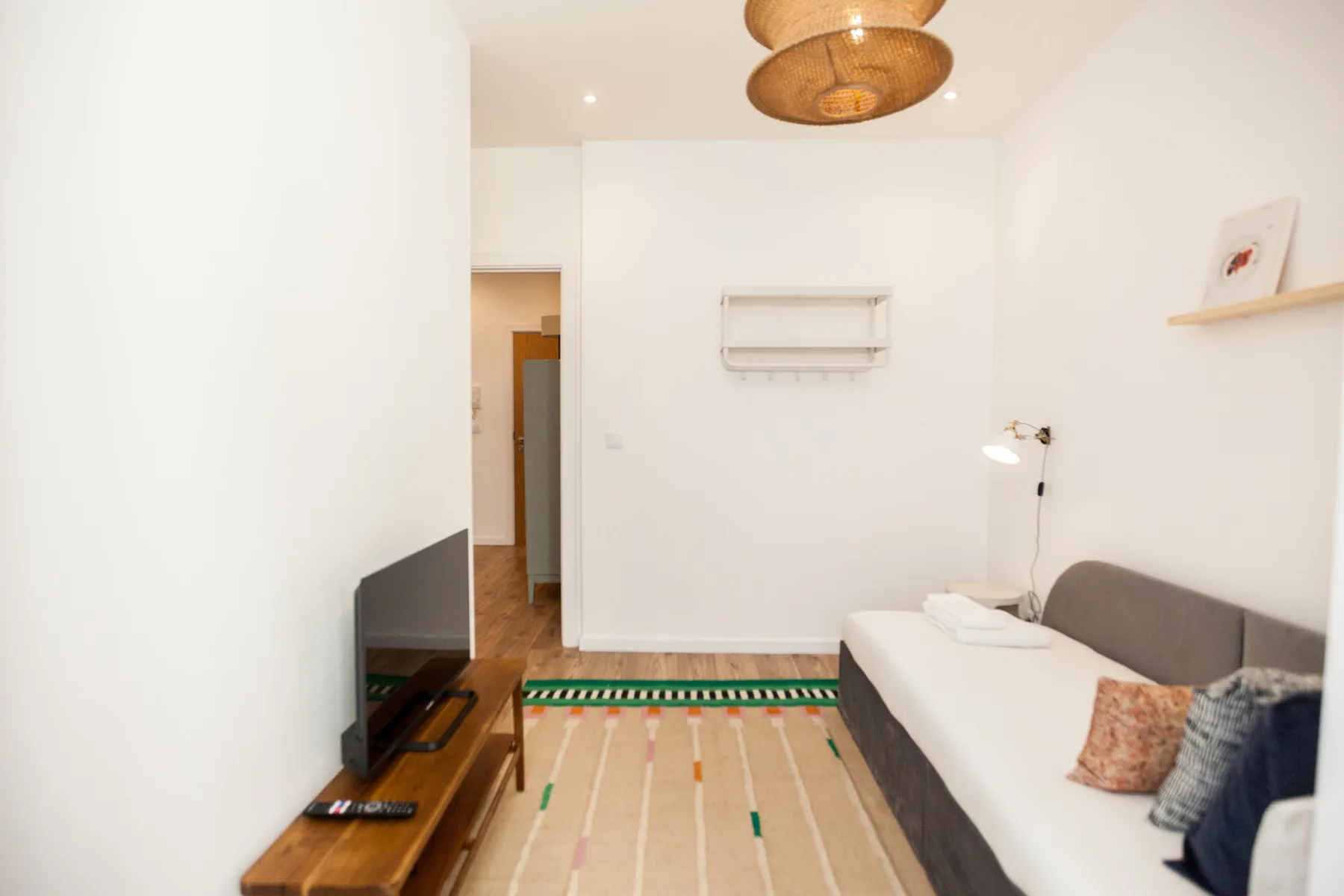 Una sala luminosa con televisor, asientos y una alfombra a rayas.