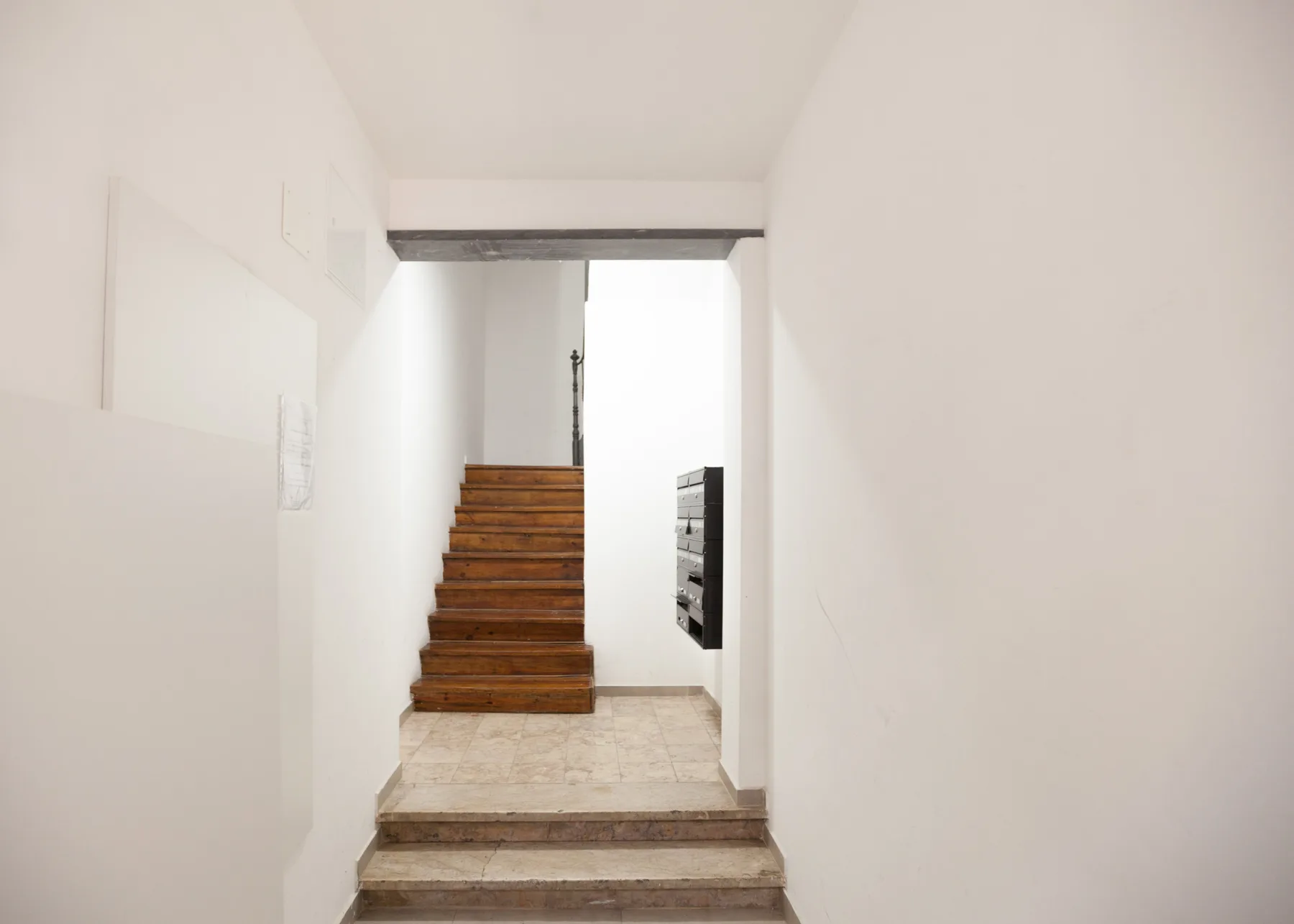 Un pasillo luminoso conduce a una escalera de madera.
