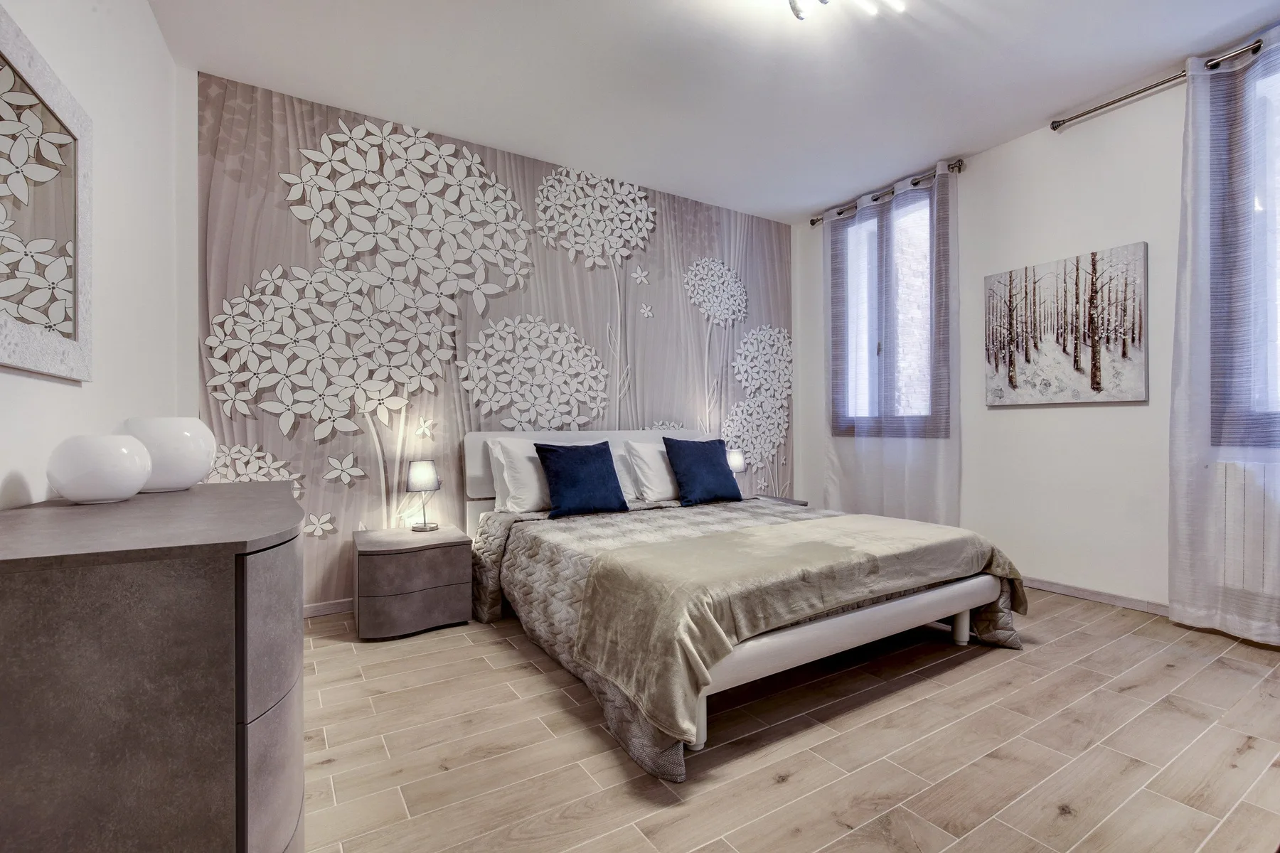 Un dormitorio con una cama grande, paneles decorativos en la pared y ventanas altas.
