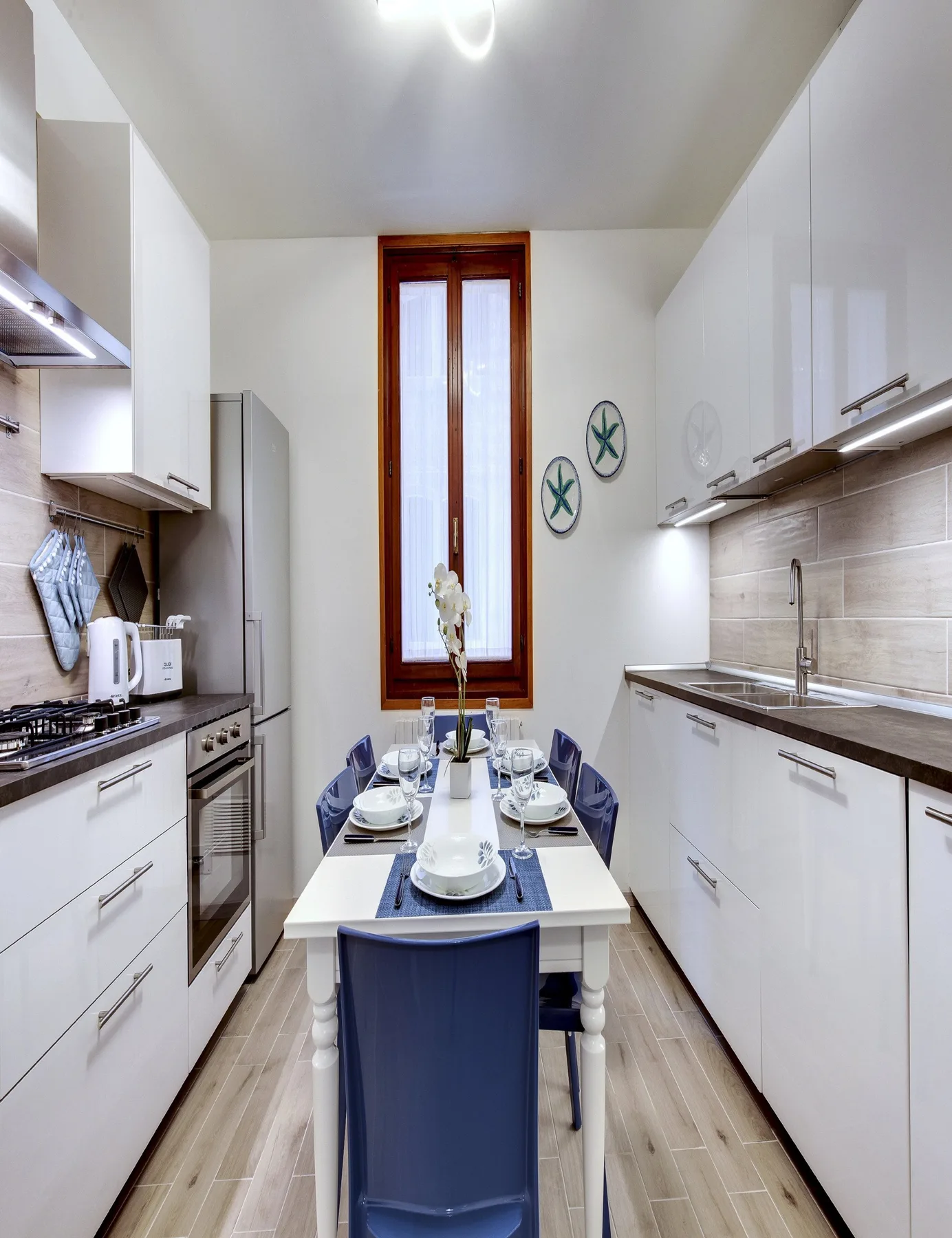 Una cocina luminosa con armarios blancos y una mesa de comedor junto a la ventana.