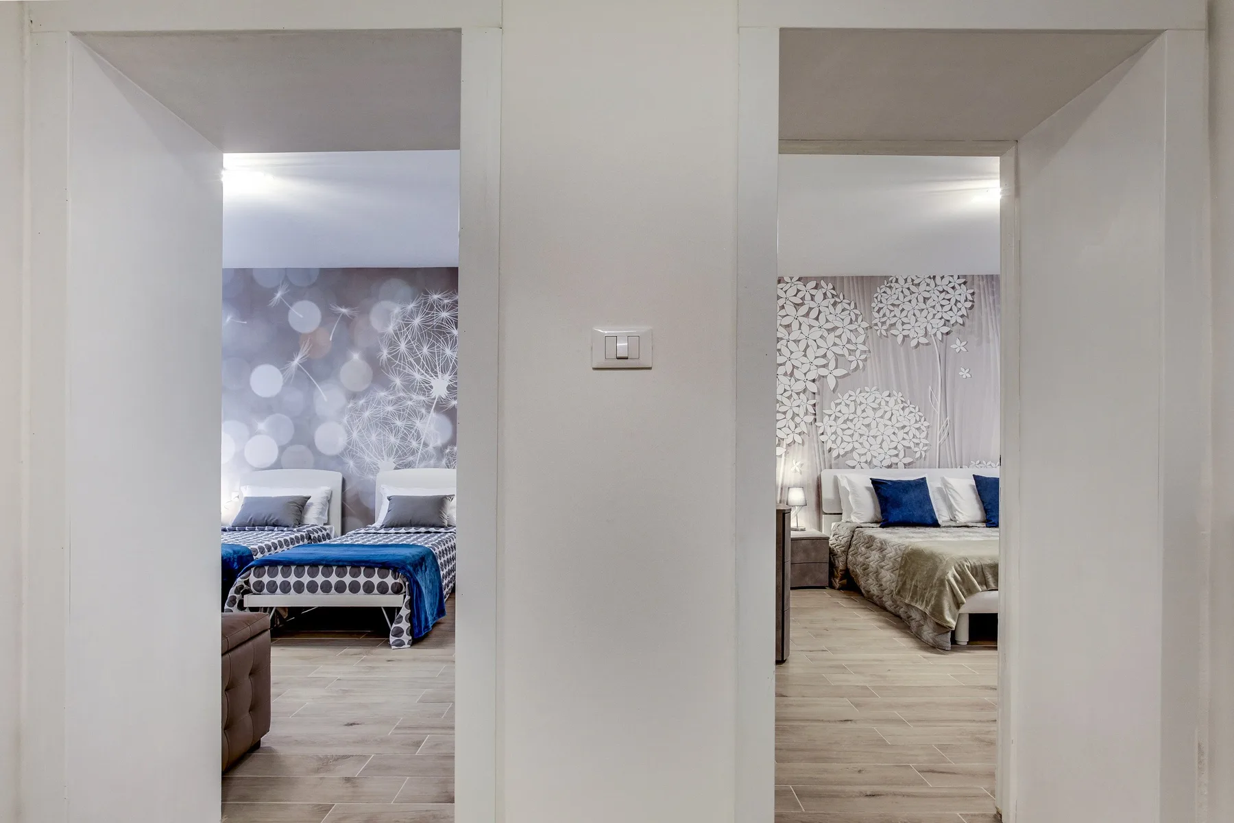 Una vista a través de dos puertas muestra dormitorios con paredes estampadas y camas.