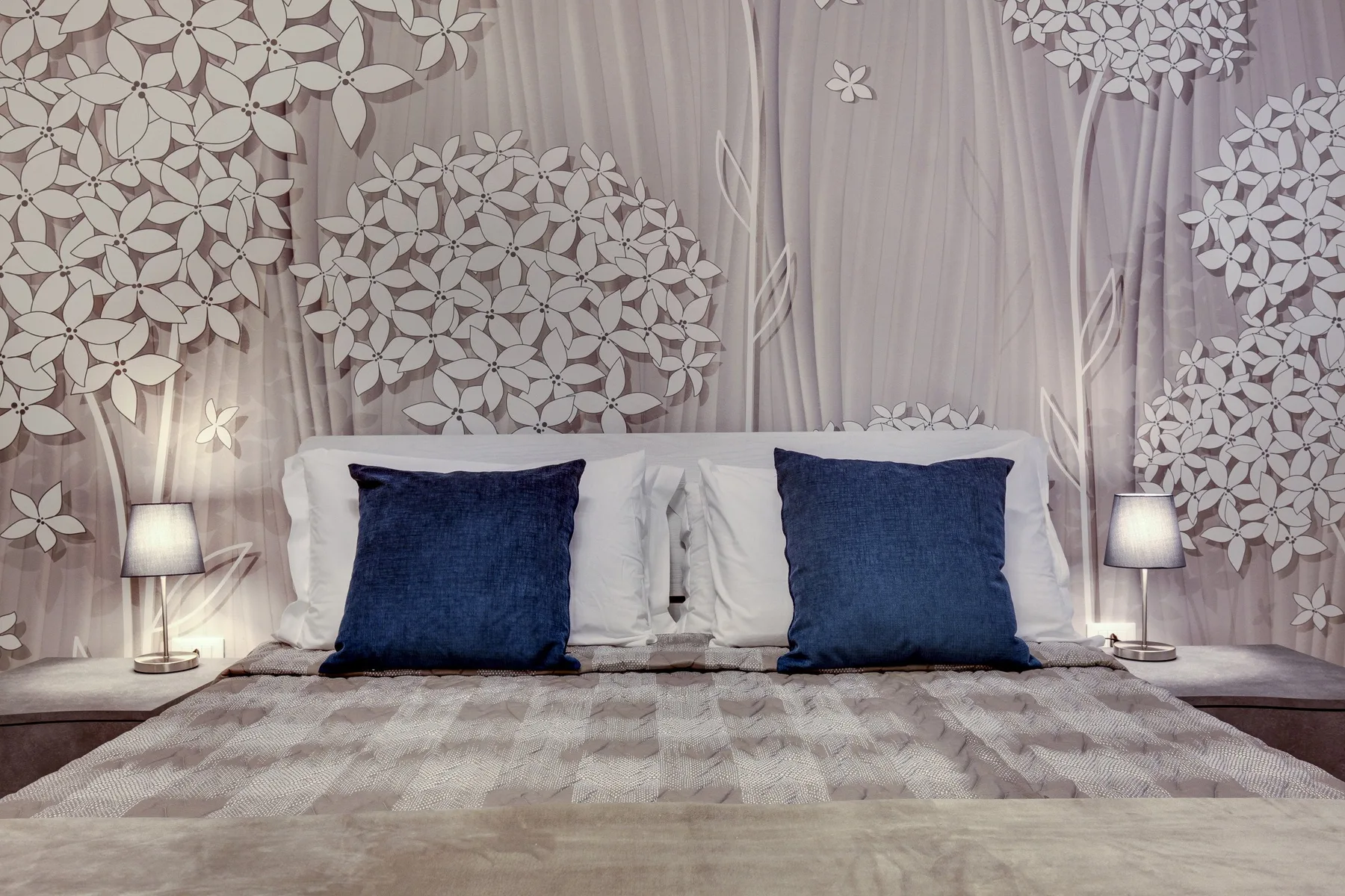 Un dormitorio con una cama vestida con ropa de cama neutra y almohadas azul oscuro.