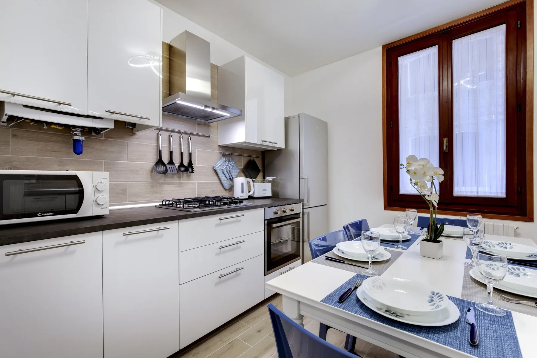 Una cocina luminosa con armarios blancos y una mesa de comedor junto a la ventana.