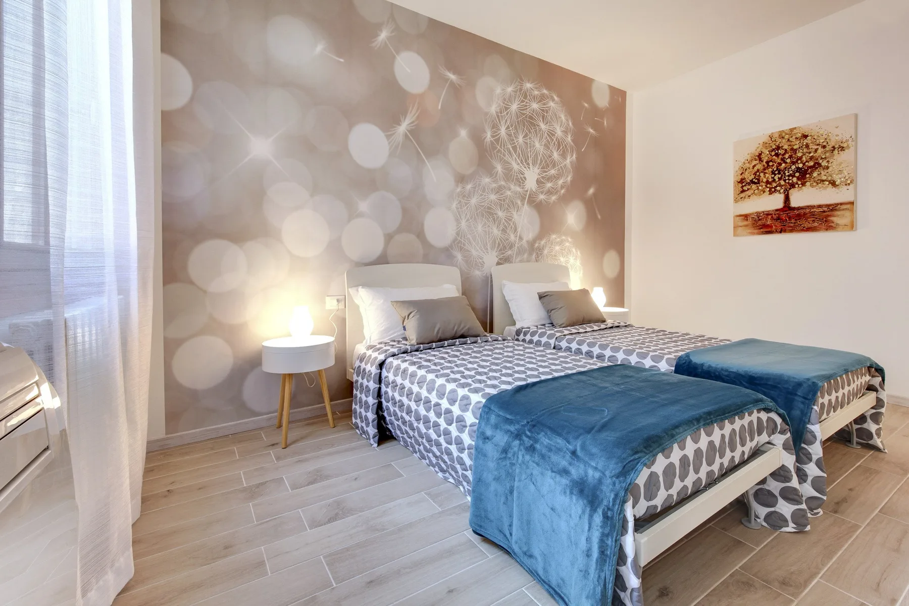 Un dormitorio con dos camas, ropa de cama estampada y mantas azules.