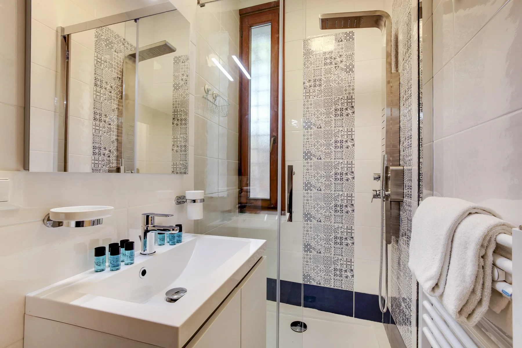 Un baño luminoso con lavabo, espejo y ducha de vidrio.