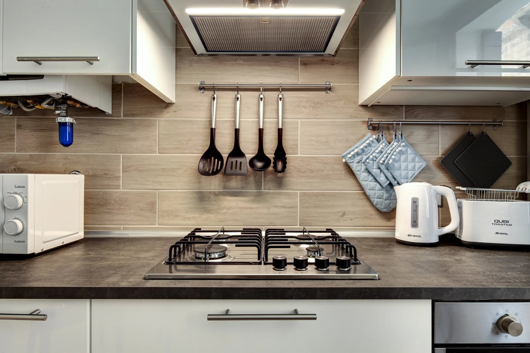 Una cocina moderna con una placa de gas bajo una campana extractora.