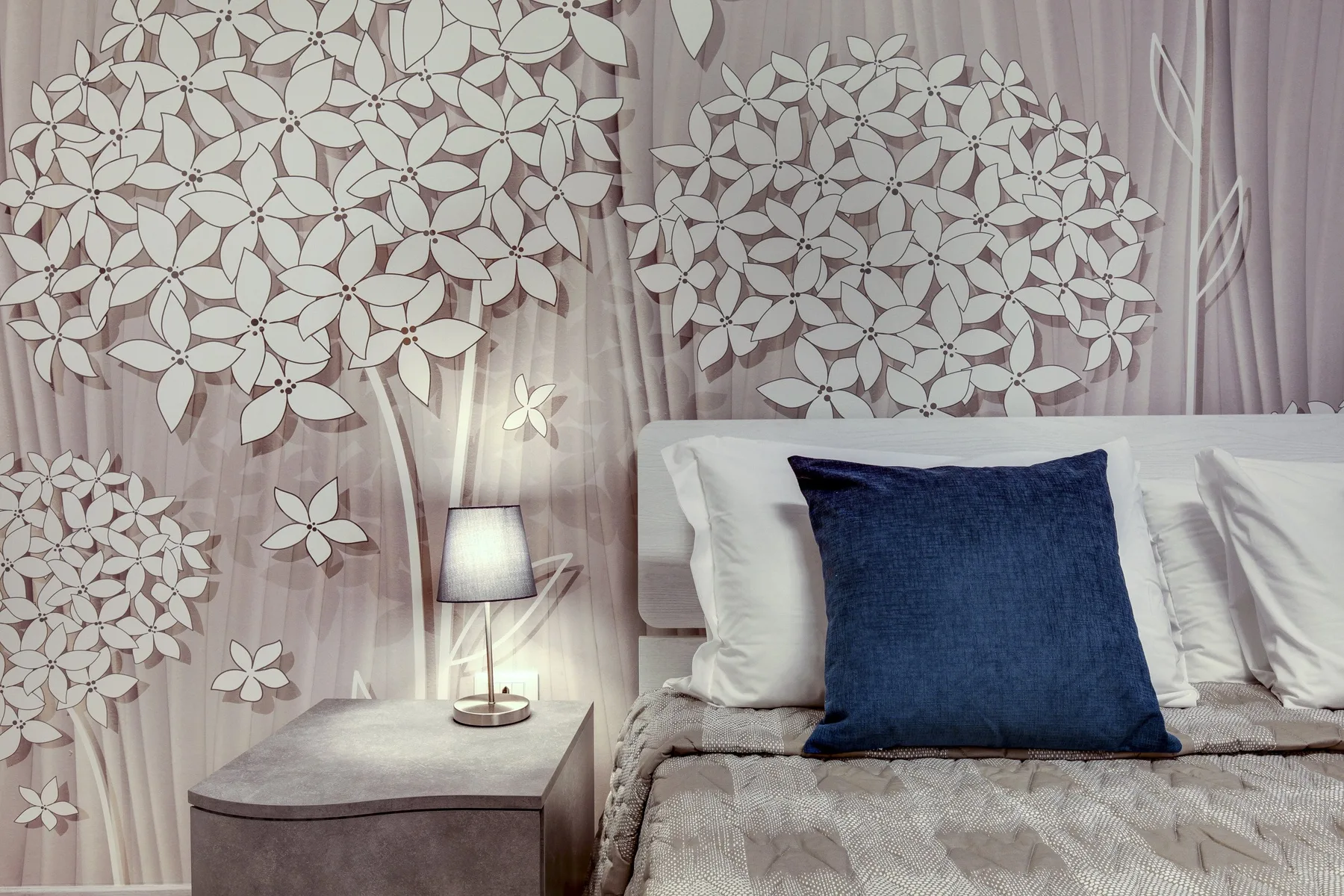 Un dormitorio con una cama y diseños florales decorativos en la pared.