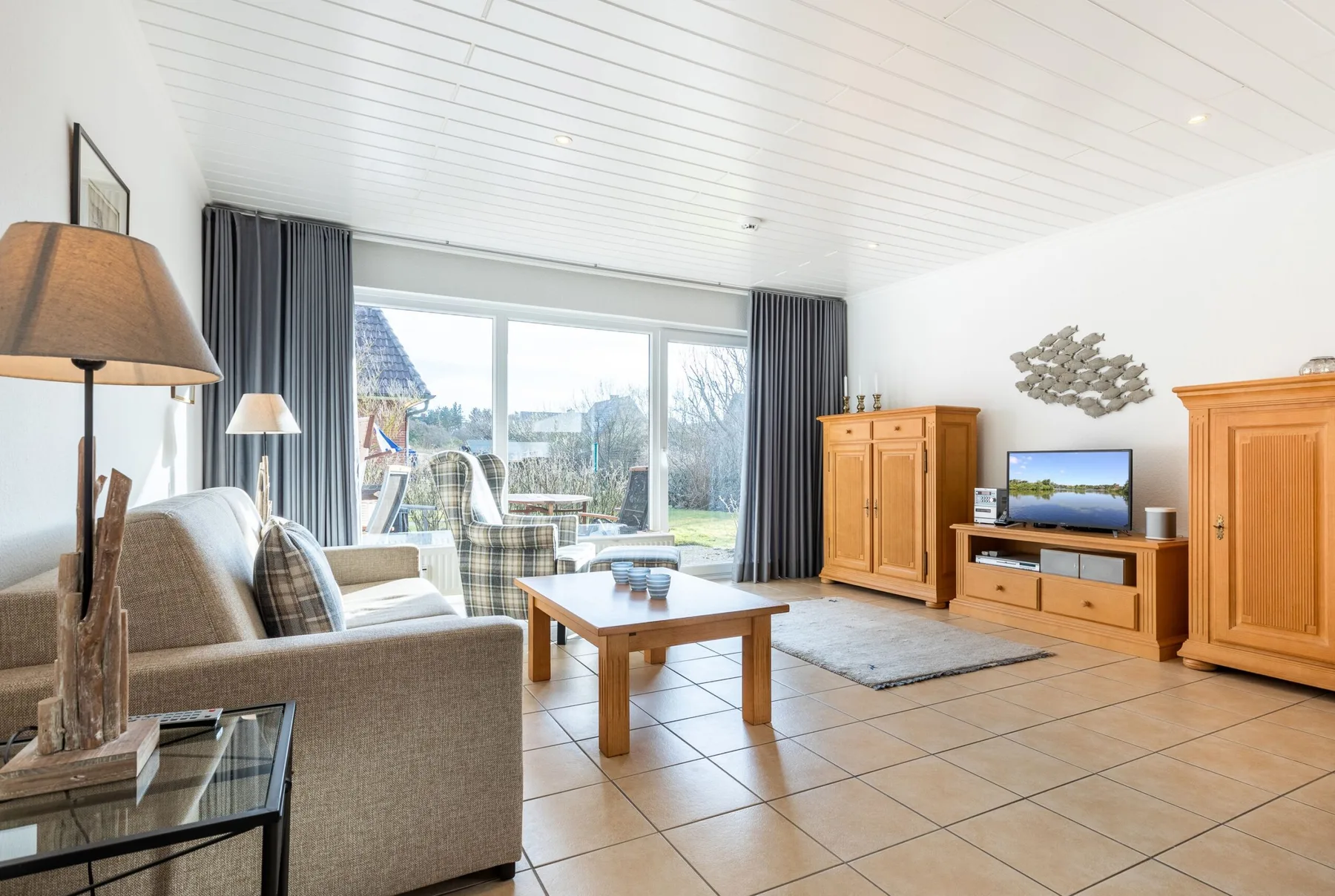 A bright living room with seating, a coffee table, and large windows.