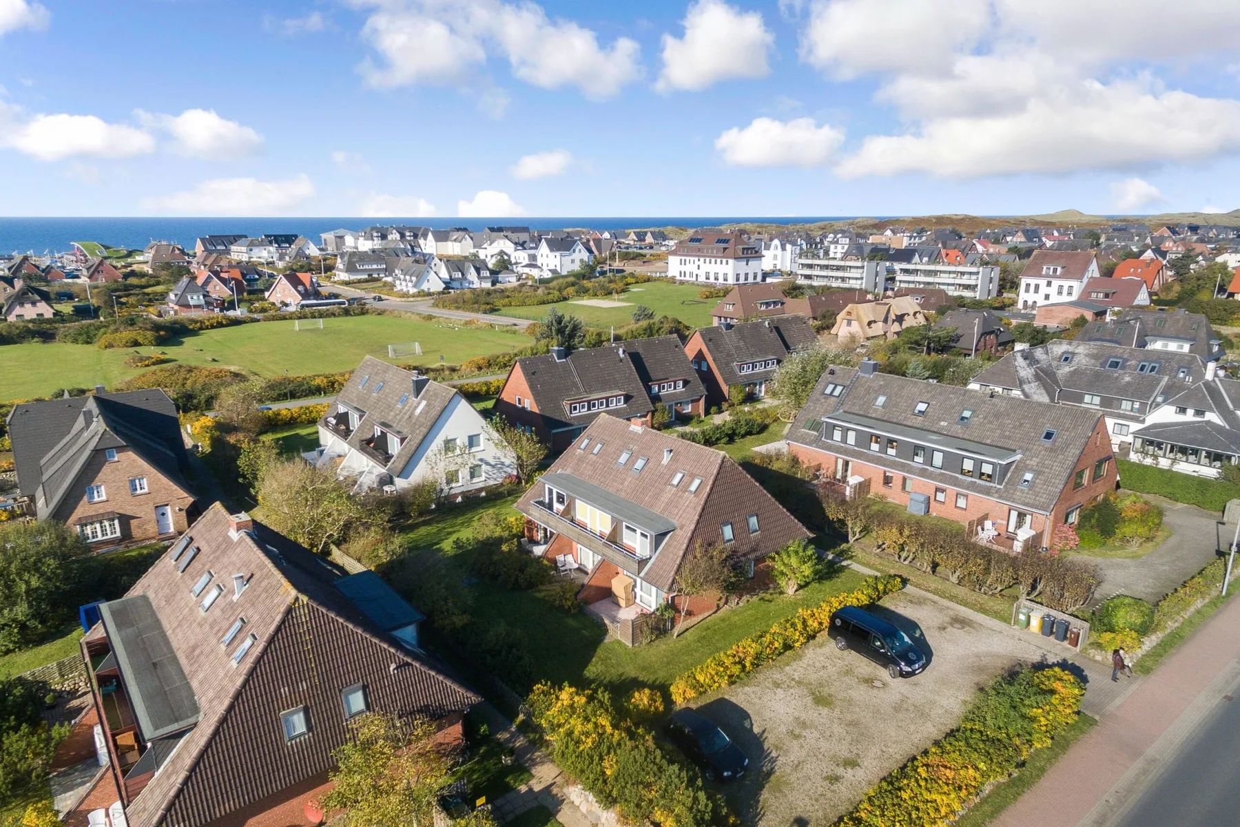 Aerial view of a coastal neighborhood with houses and the sea in the distance.