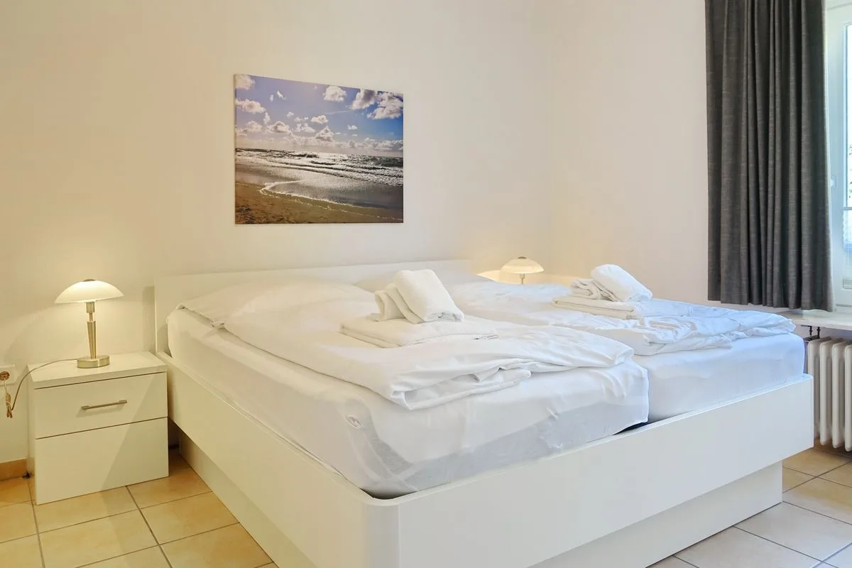 A bedroom with a large bed, folded towels, and bedside lamps.