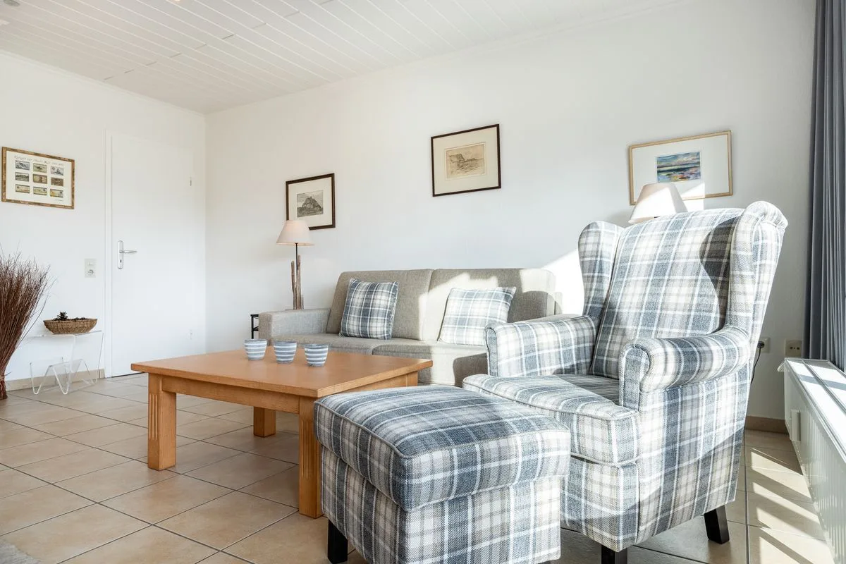 A bright living room with plaid seating and a wooden coffee table.