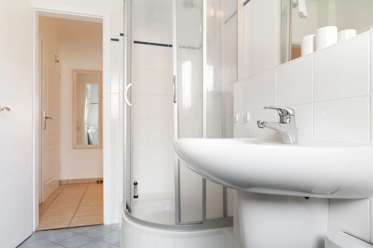 A bright bathroom with a curved shower enclosure and a white sink.