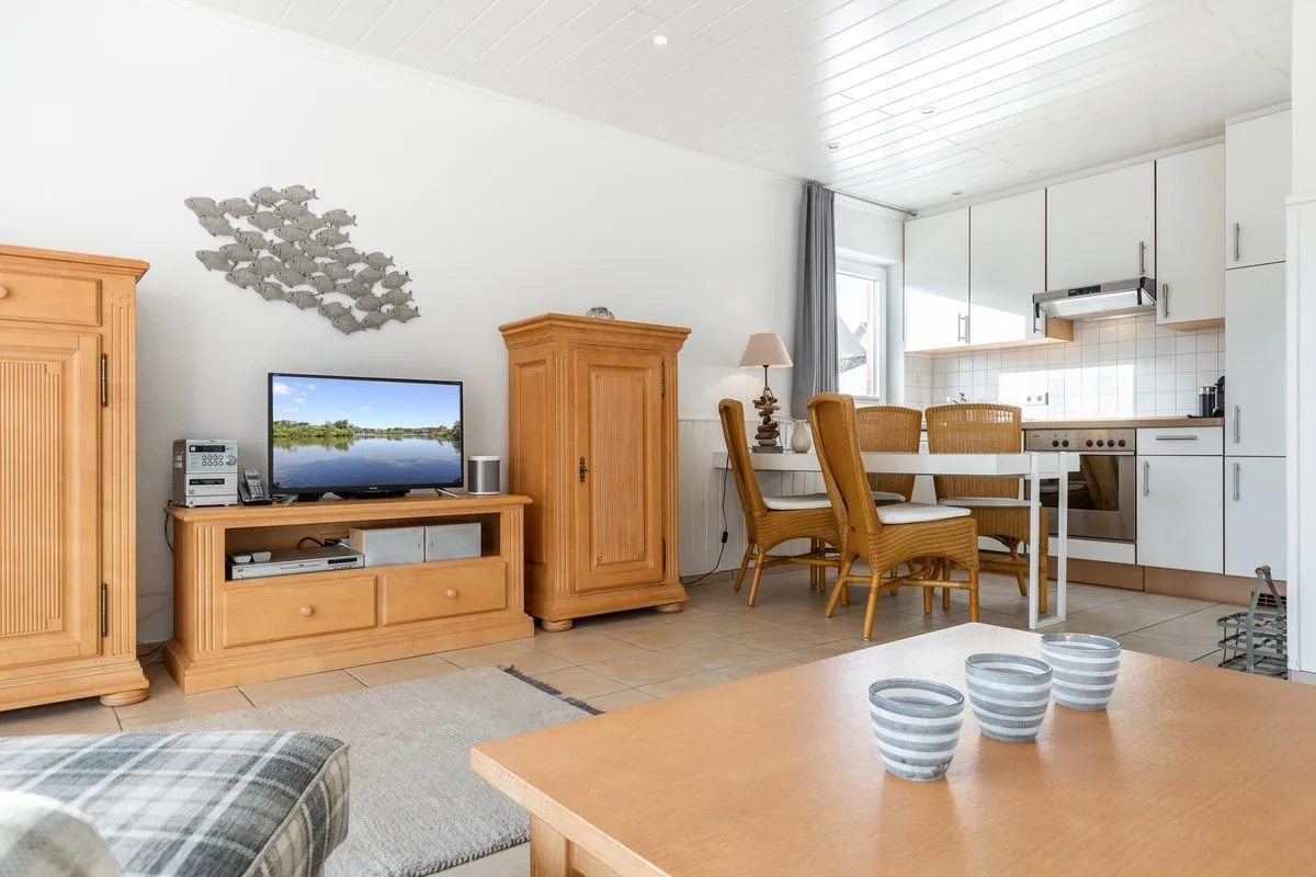 A bright living and dining area opens onto a compact kitchen, with a television and dining table.