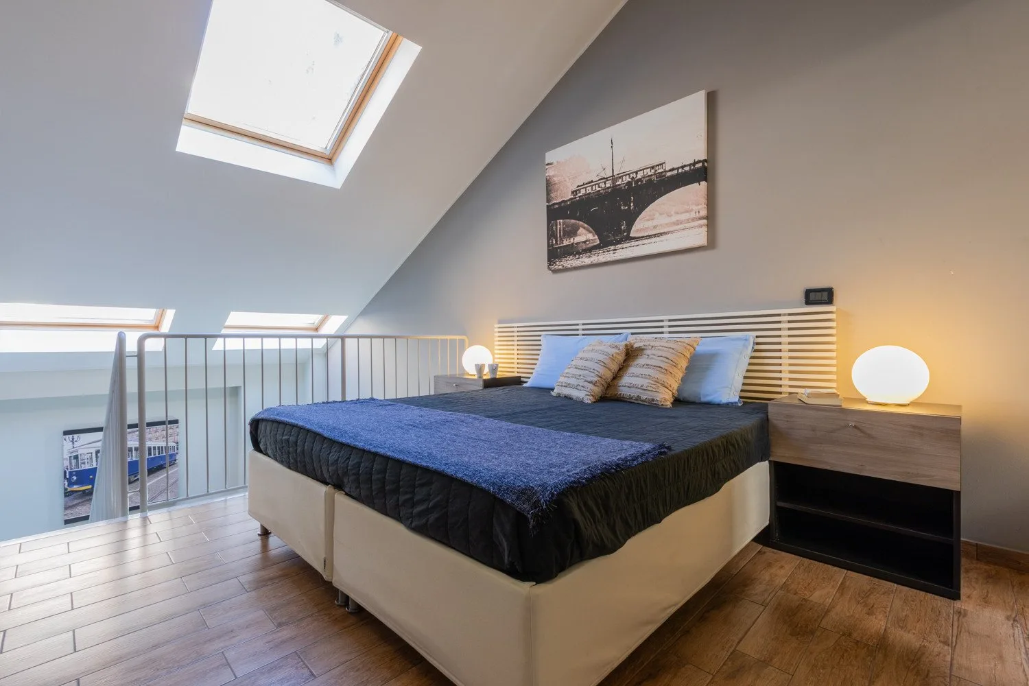 Un dormitorio con una cama bajo un techo inclinado y tragaluces.