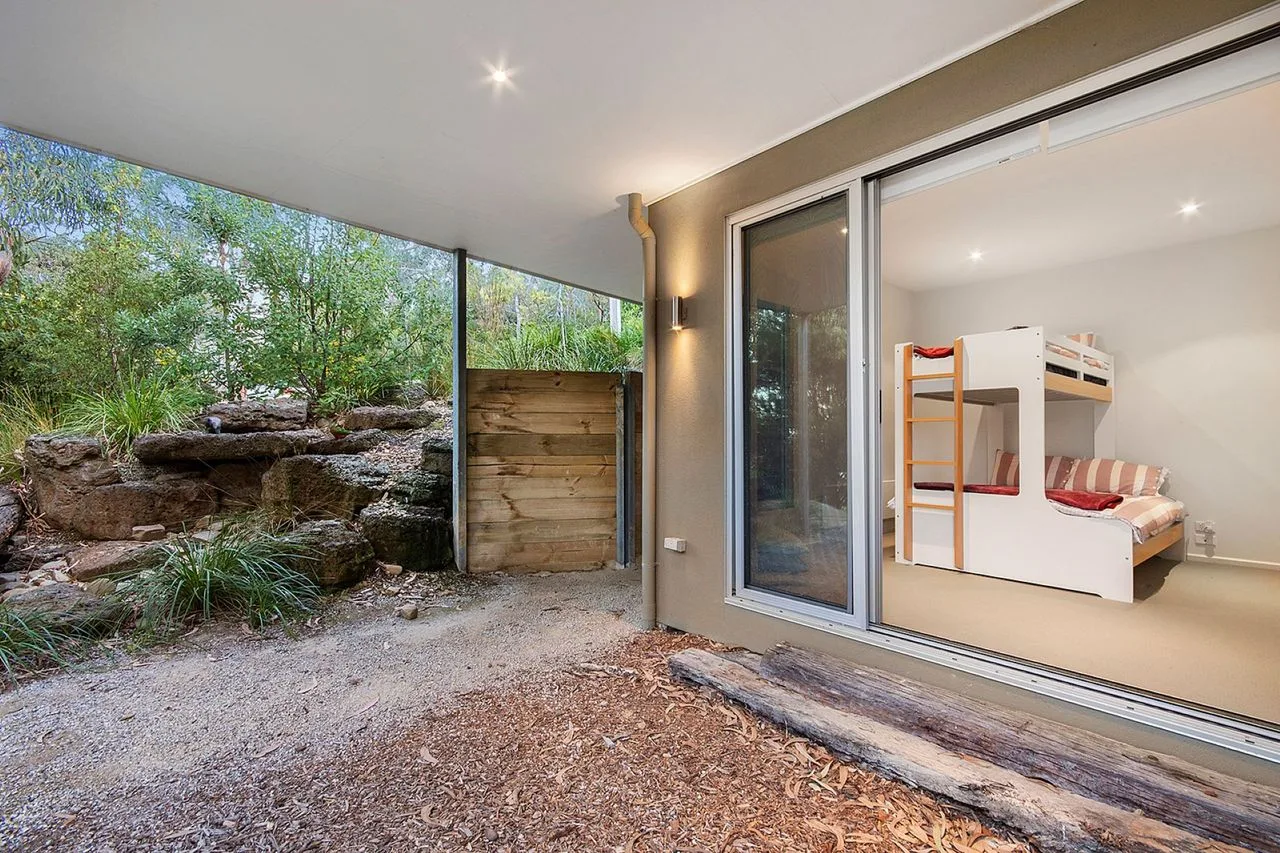 A covered patio opens onto a garden, with a bunk bed visible indoors.
