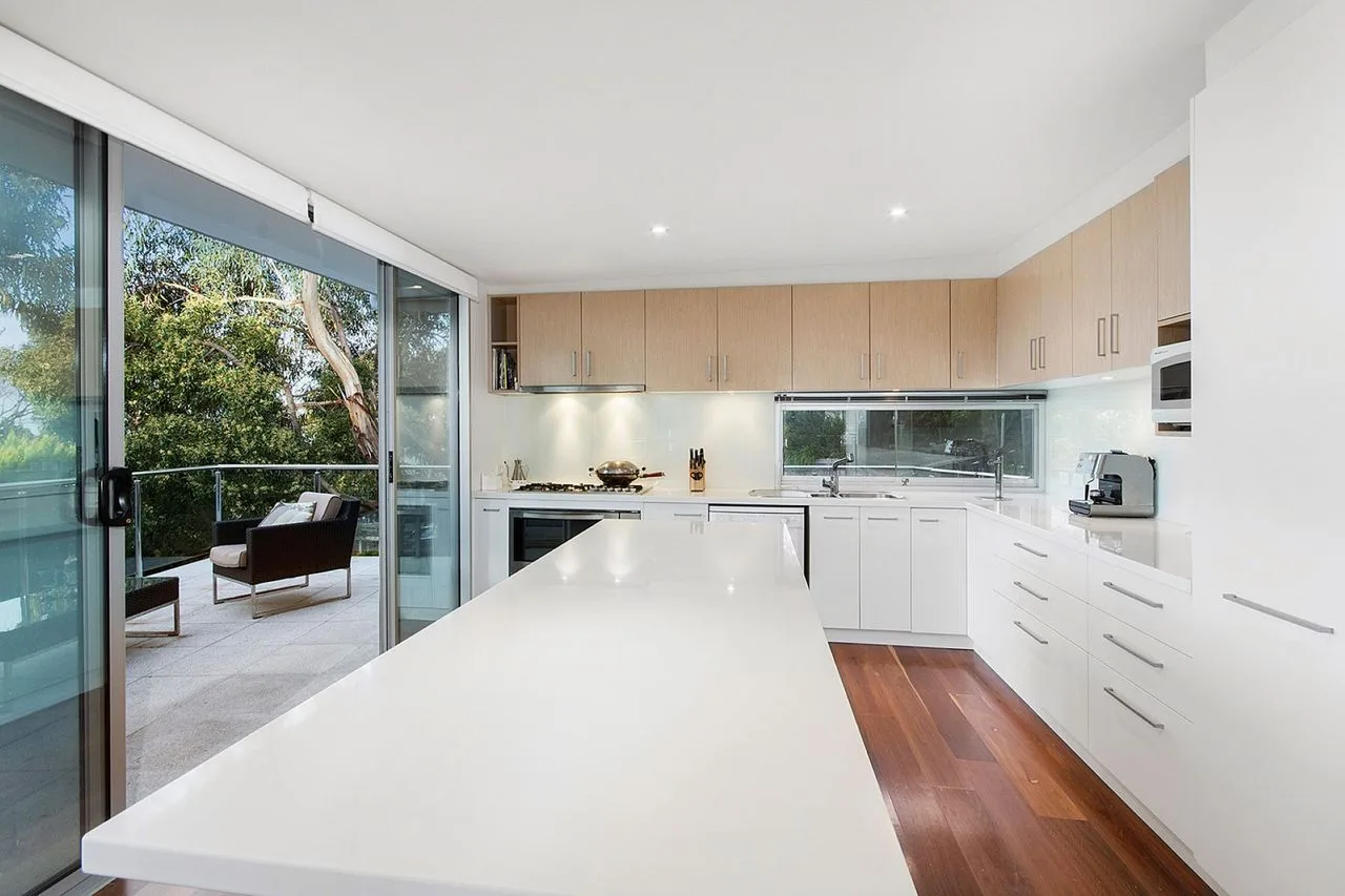 A bright modern kitchen opens onto a patio with outdoor seating.
