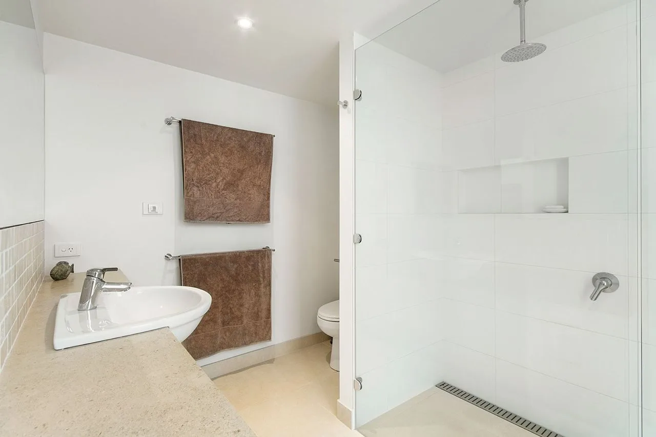 A bright bathroom with a sink and a glass-enclosed shower.