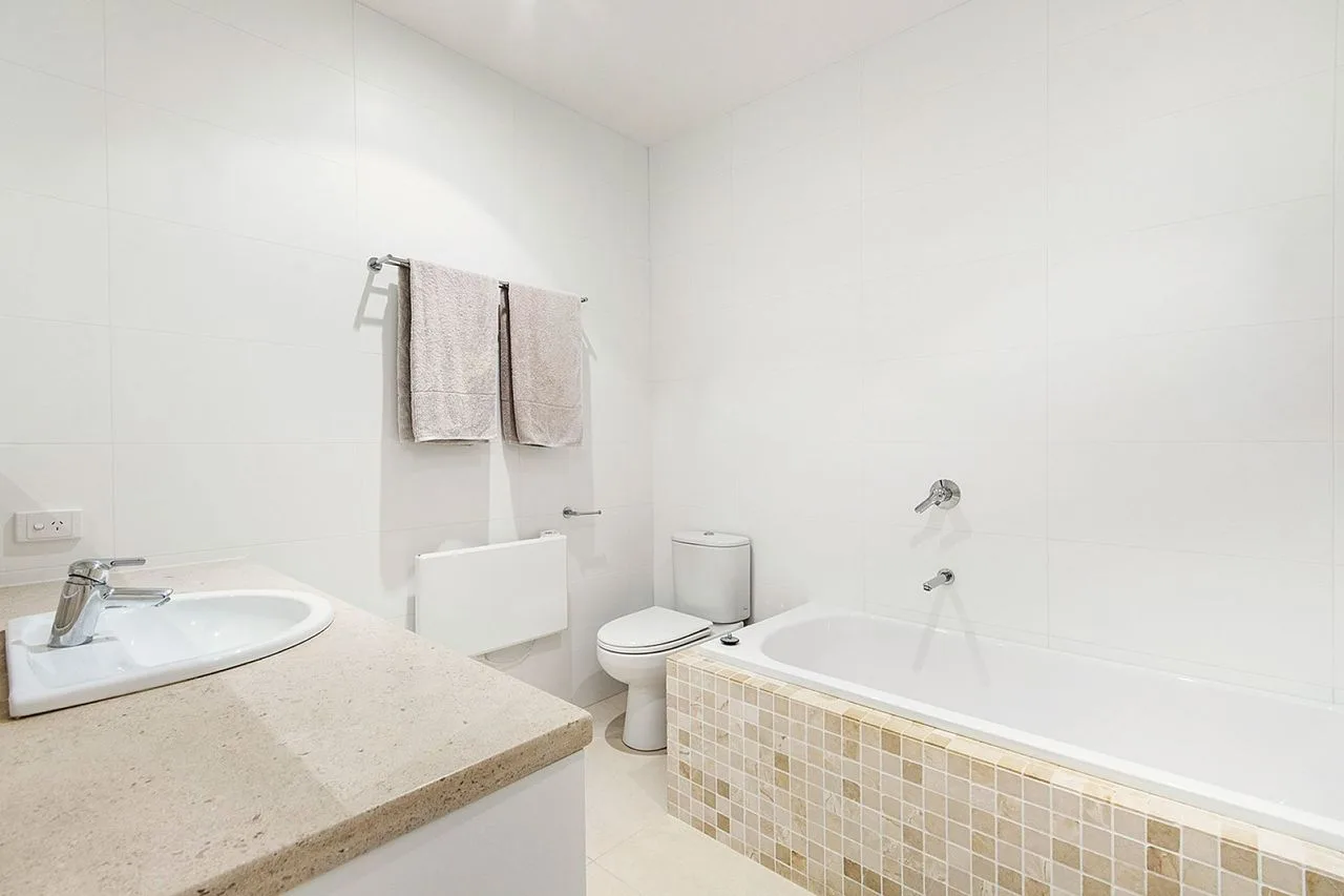 A bright bathroom with a bathtub, sink, and hanging towels.