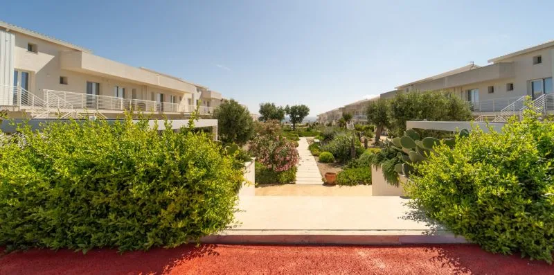 A landscaped garden path runs between rows of modern residential buildings.