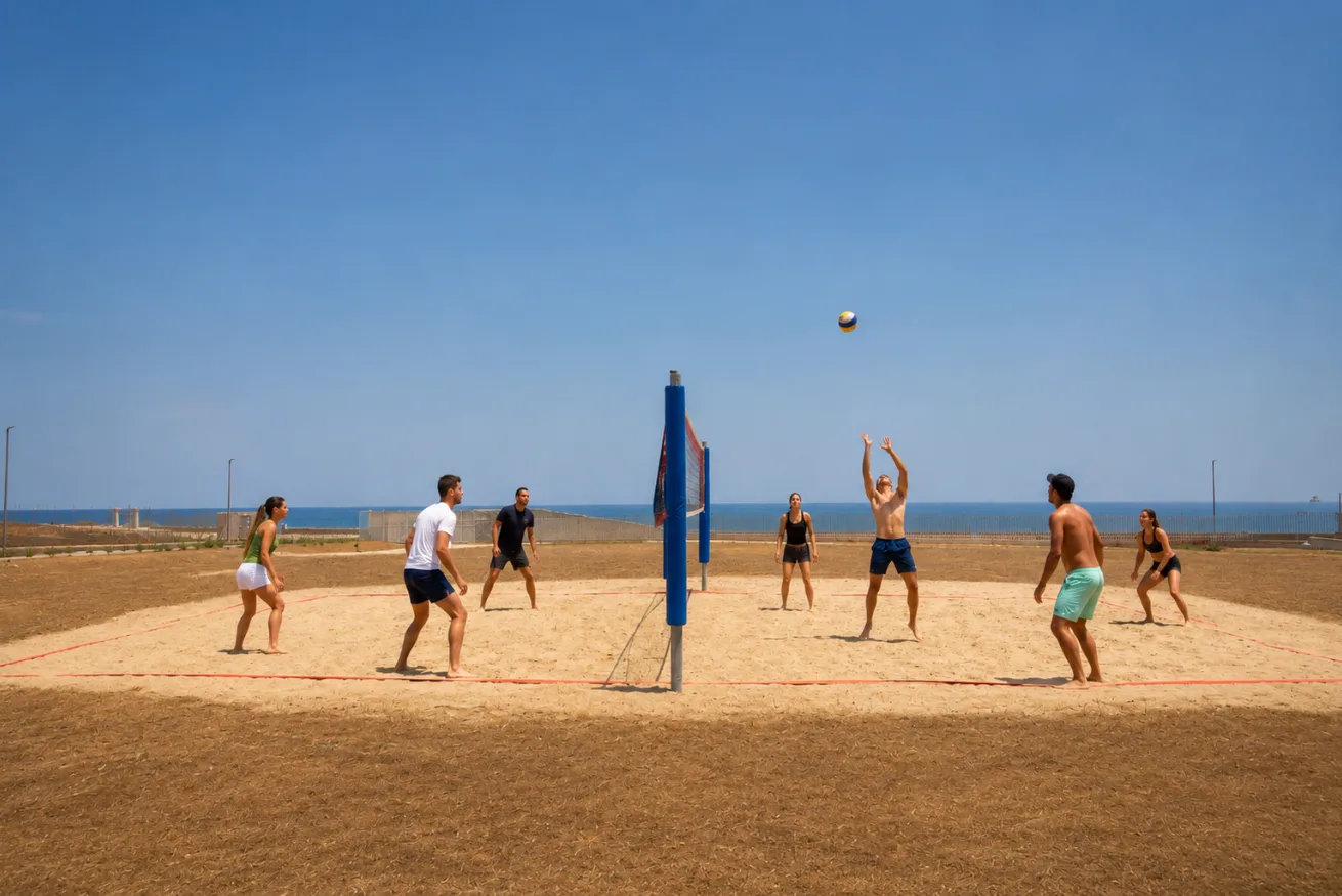 A beach volleyball game takes place on a sandy court beneath a clear sky.