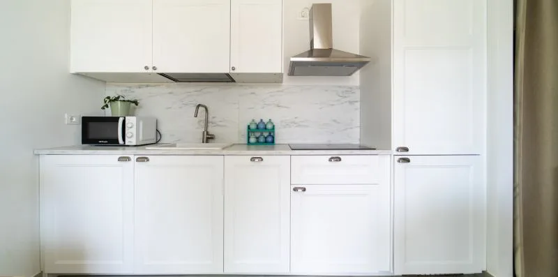 A bright white kitchen with cabinets, a countertop, and a stainless steel range hood.