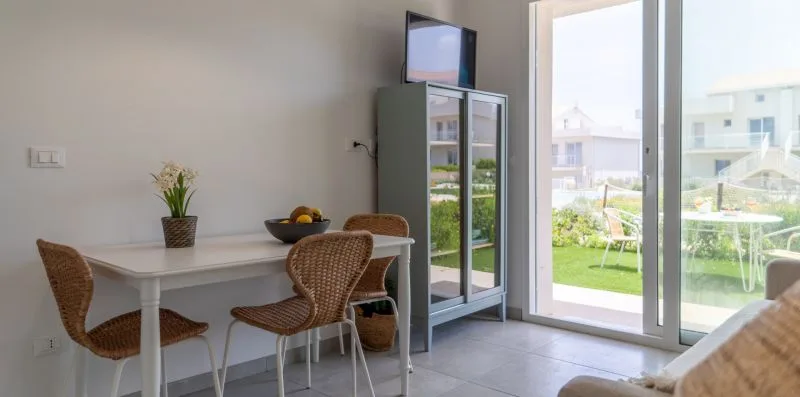 A dining area with a table and chairs beside large glass doors.