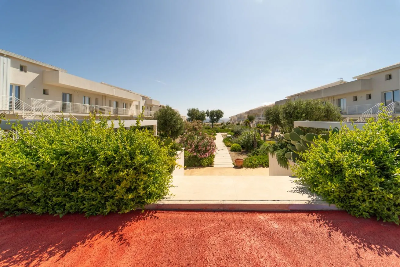 A landscaped walkway runs between rows of light-colored residential buildings.