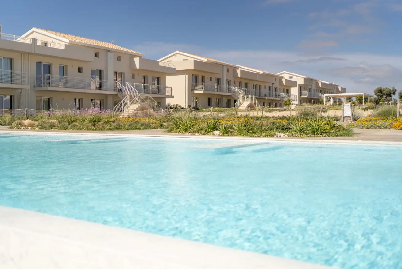 A swimming pool in front of a row of modern apartment buildings.
