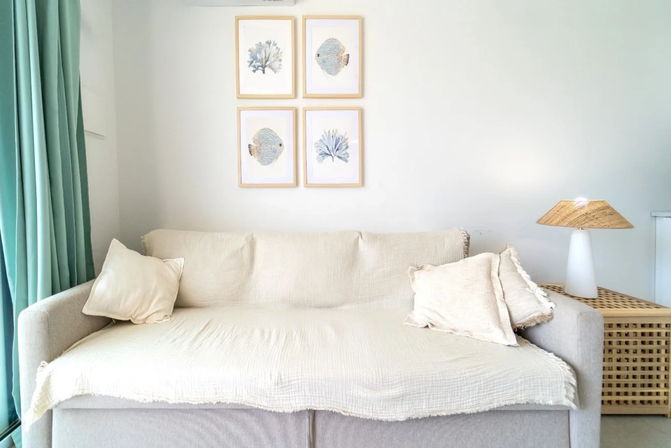 A bright living room with a cream sofa, teal curtains, and framed prints.